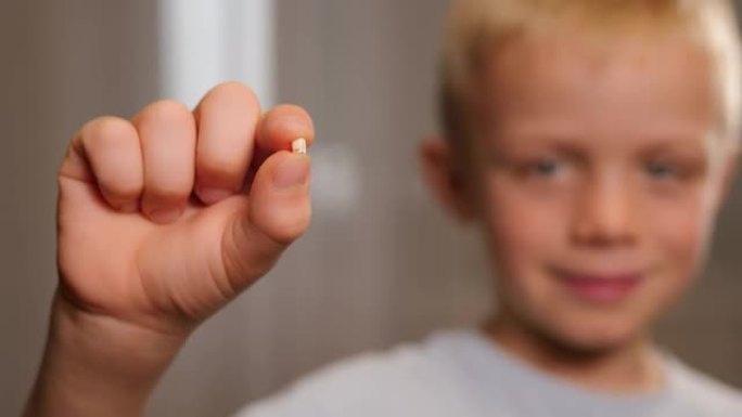 一个小男孩手里拿着一颗倒下的乳牙的特写镜头。