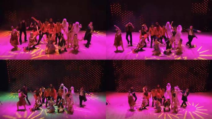 疯狂的人在现代剧院的舞台上在五颜六色的灯光中跳舞