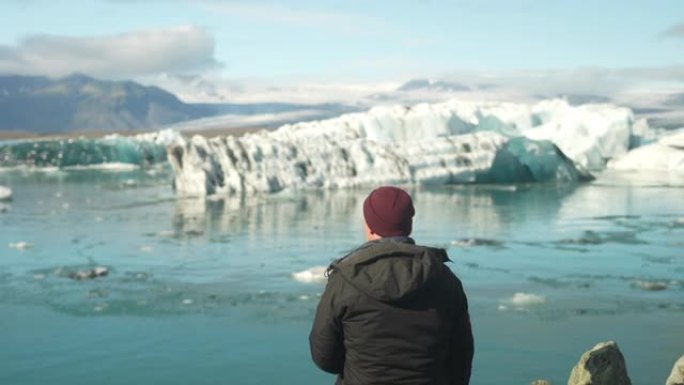 一名男子看着Jokulsarlon冰川泻湖的背景图