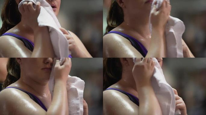 女人用毛巾擦汗，在健身房运动后疲倦，体重减轻