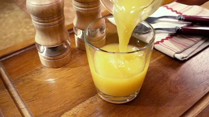 橙汁倒入玻璃杯中，早晨早餐。旋转跟踪镜头慢动作。
