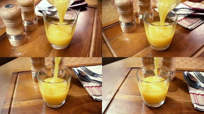 橙汁倒入玻璃杯中，早晨早餐。旋转跟踪镜头慢动作。