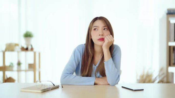 工作分心担心年轻的亚洲女性想到问题。沉思无动力的女士看着窗户，感到精力不足