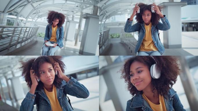 年轻的非洲裔美国妇女在城市上戴上耳机并欣赏音乐，女性听音乐，歌曲，播客或有声读物，在万向节上缓慢移动
