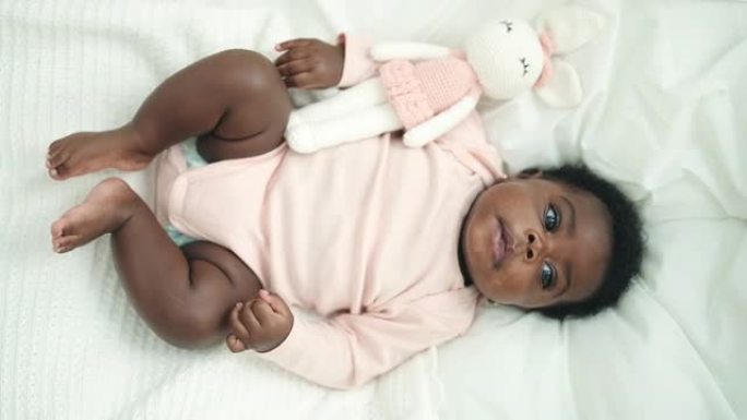 非裔美国人婴儿躺在床上，在卧室里表情轻松