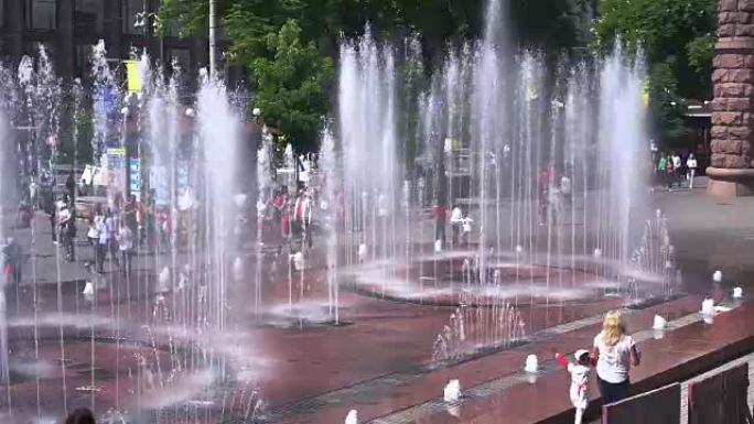 城市炎热的夏季周末，家庭在喷泉附近散步，孩子们在玩耍