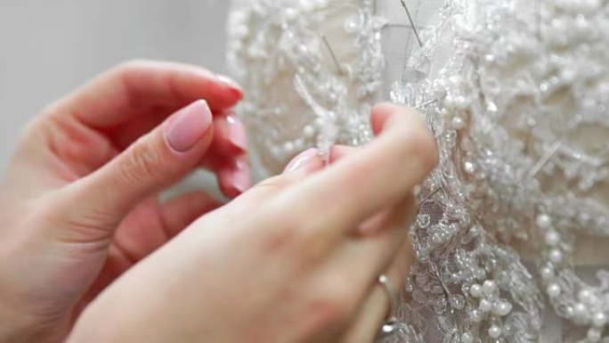 在他的工作室为新娘准备的特写时装设计师pinse needles蕾丝婚纱。女裁缝打造专属婚纱。用针脚