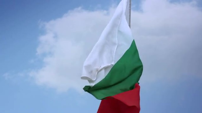 蓝天中，旗杆上飘扬着保加利亚国旗。保加利亚