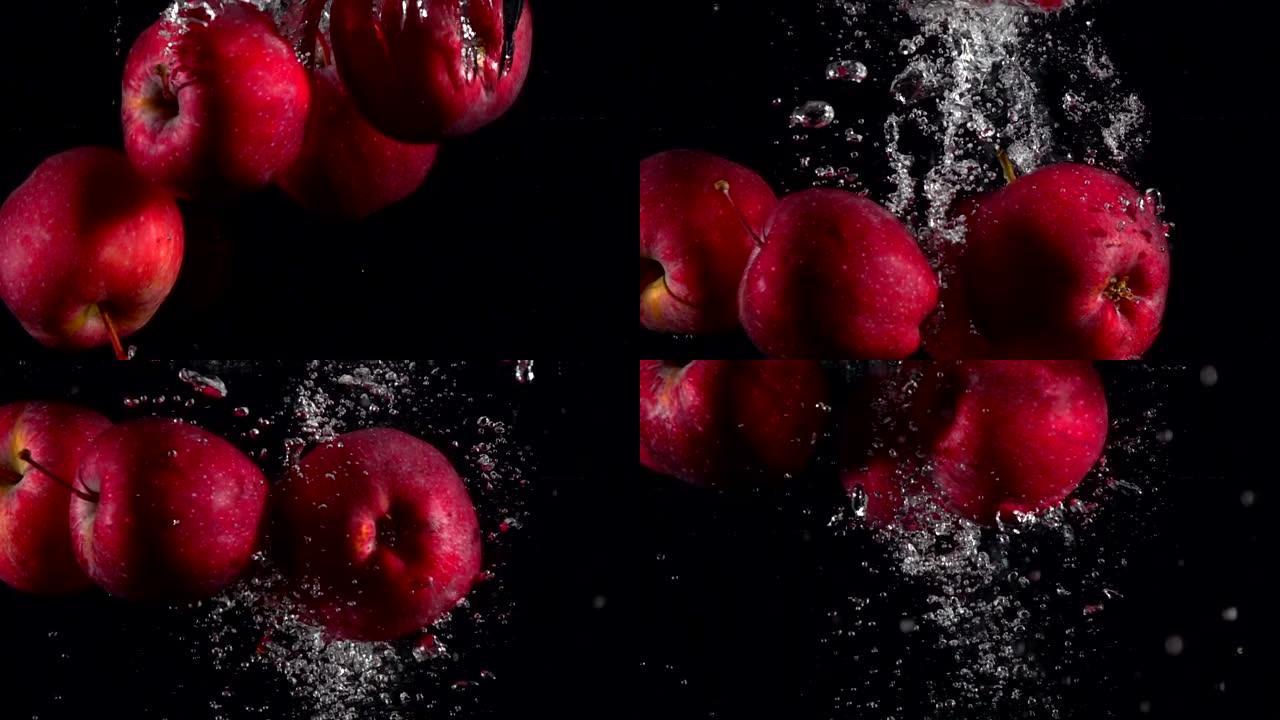 慢动作红苹果在黑色背景下落水。美丽的新鲜水果在水族馆里飞溅。有机水果，健康食品，饮食，概念。以4k 