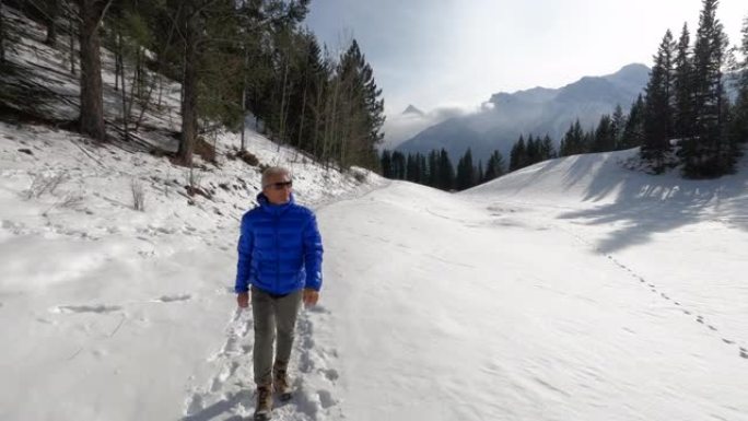 成熟的人沿着山路在雪中徒步旅行