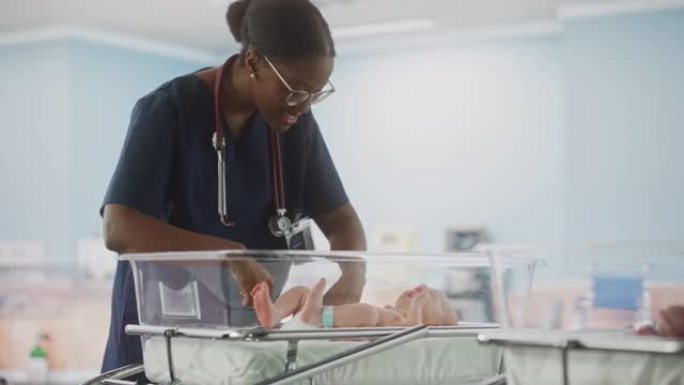 可爱的高加索新生婴儿躺在产科医院的摇篮里。美丽的黑人儿科医生检查一个孩子。医疗保健、怀孕和孕产概念