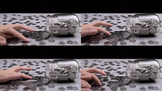 女性手从倒玻璃罐中数桌子上散落的硬币