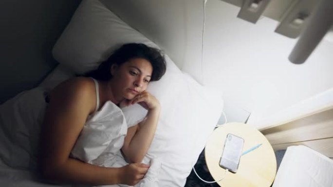 女人晚上躺在床上睡不着。半夜失眠的人在沉思中感到压力