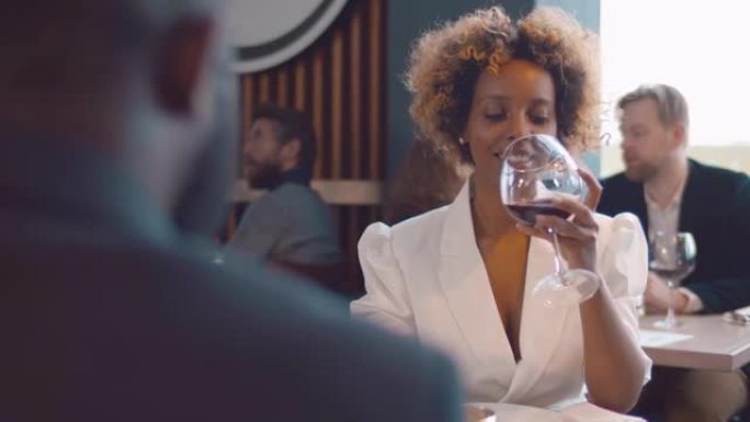 快乐的非裔美国人夫妇在高档餐厅喝酒享受浪漫的约会。实时