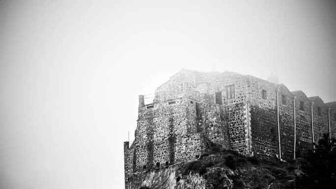 站在雾蒙蒙的山顶上的黑白神秘闹鬼城堡