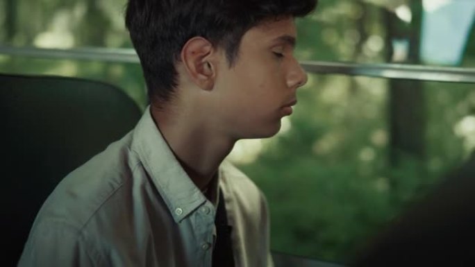 印度男孩独自坐校车特写。青少年男生看窗户。