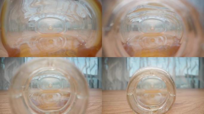 罐子里的蜂蜜从墙上流下。摄像机从罐子里滑出。我拿着罐子，极端特写