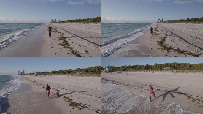 跟踪肌肉发达的男运动员在海岸线上奔跑的航拍画面
