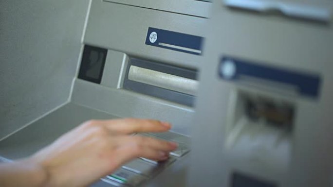 女人按下正确的按钮，在自动取款机上插入她的密码，银行