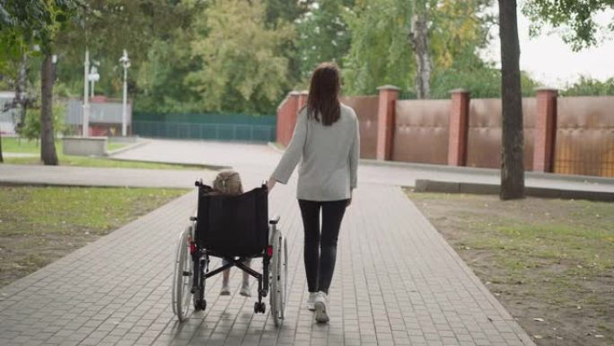 母亲帮助小女儿在轮椅上移动