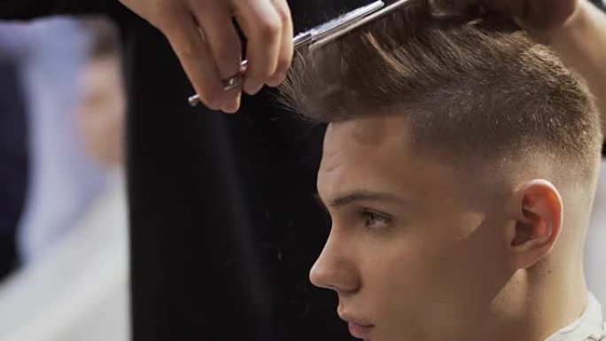发型师用剪刀剪掉年轻人的头发