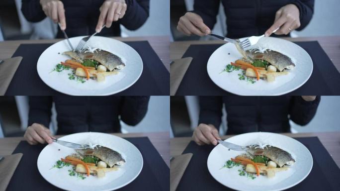 一个女人吃鱼和蔬菜餐的特写镜头
