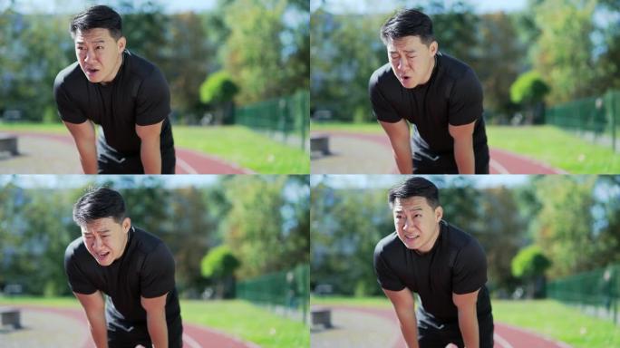 一名成年亚洲跑步者在城市体育场的跑步机上快速冲刺后呼吸急促。穿着运动服的运动员倾斜