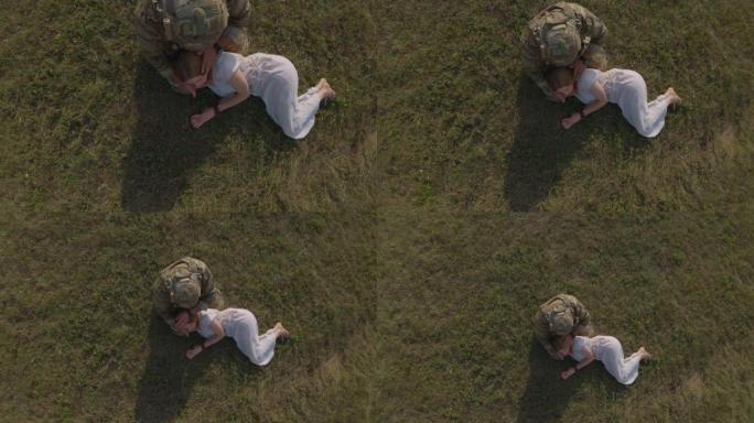 美丽的年轻金发女子在亚麻连衣裙躺在眼睛闭上士兵迷彩服谁抚摸她的头与他的手膝盖。乌克兰战争的概念，守军