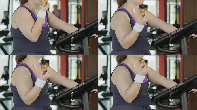 肥胖的年轻女子意志力弱，在健身房锻炼时吃甜甜圈