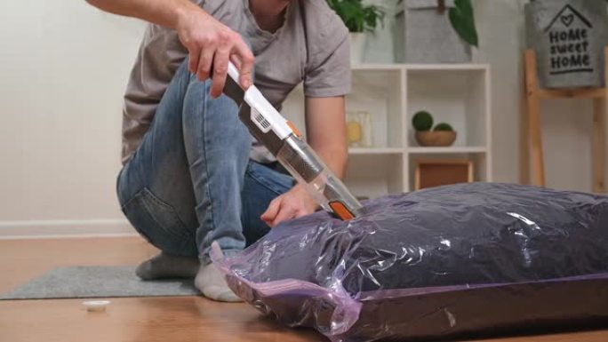 一名男子使用手动真空吸尘器从真空袋中清除空气。