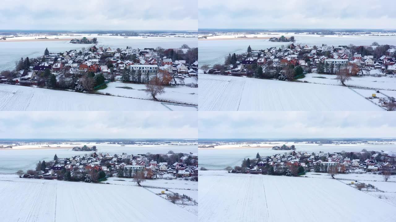 从德国北部一个村庄边缘的鸟瞰图在白雪覆盖的白色田野之间