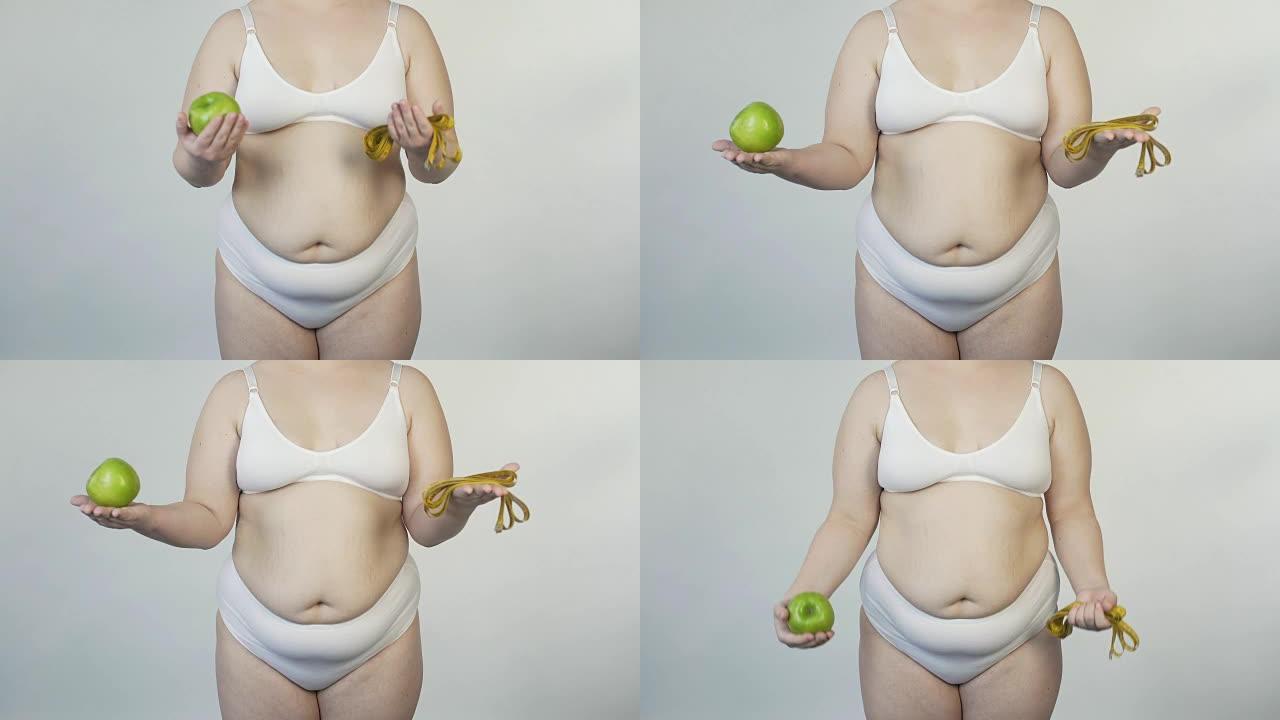 丰满的女性在相机前展示苹果和胶带线，健康的生活方式，饮食