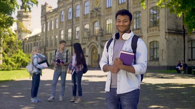 优秀的学生站在大学附近，对着镜头真诚地微笑