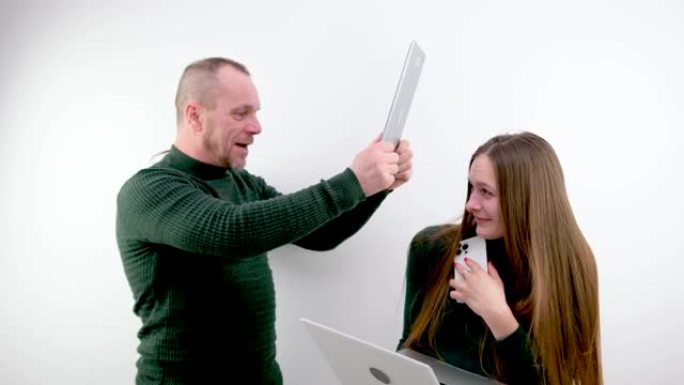 工作中的暴力侵犯权利老板用平板电脑打下属的头女孩正在用手握笔记本电脑在电话上聊天学生笑话欺负很多工作