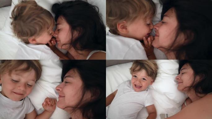 躺在床上的母亲和孩子的爱与关怀。周末妈妈和儿子爱斯基摩人亲吻的生活方式时刻