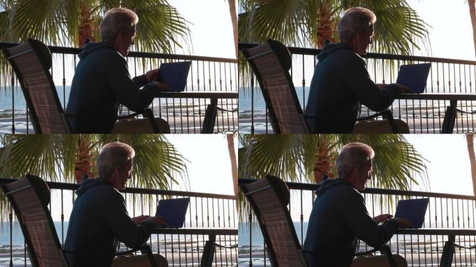 男子在热带露台上使用笔记本电脑