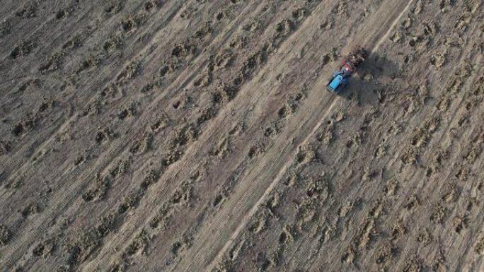 由于欧洲创纪录的干旱，农民在干燥的土壤中驾驶爬行的拖拉机的空中无人机镜头
