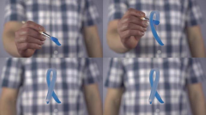 一名男子在玻璃上画了一条蓝带，以支持癌症患者。一个年轻人用刷子描绘了前列腺癌的象征。特写。4k