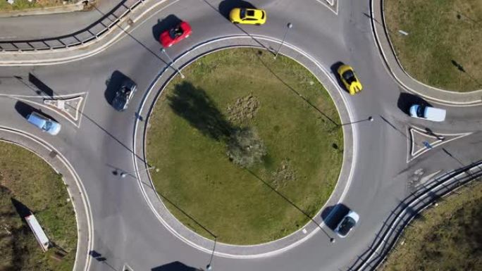 在城市郊区的绿色回旋处驾驶独家跑车的鸟瞰图，在交通时间的道路圈内的高级轿车