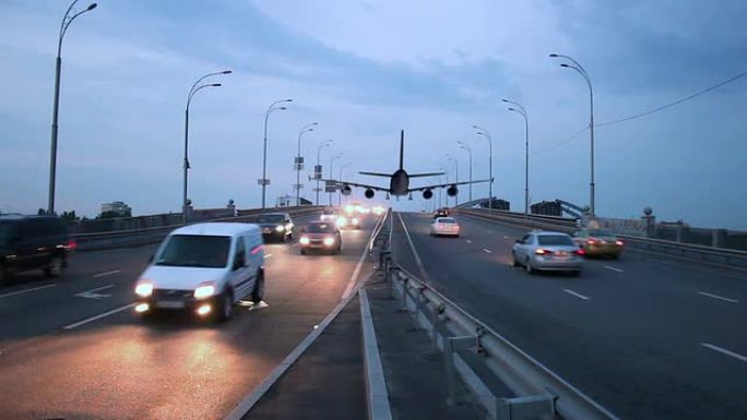 飞机降落在城市高速公路上方，交通黄昏