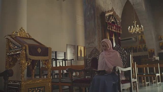 戴着头巾的漂亮女人在修道院读圣经