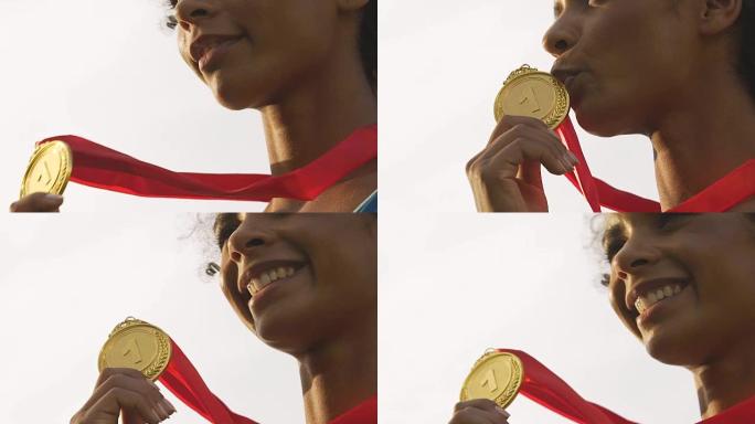 快乐的混血女运动员微笑着欢欣鼓舞胜利和金牌