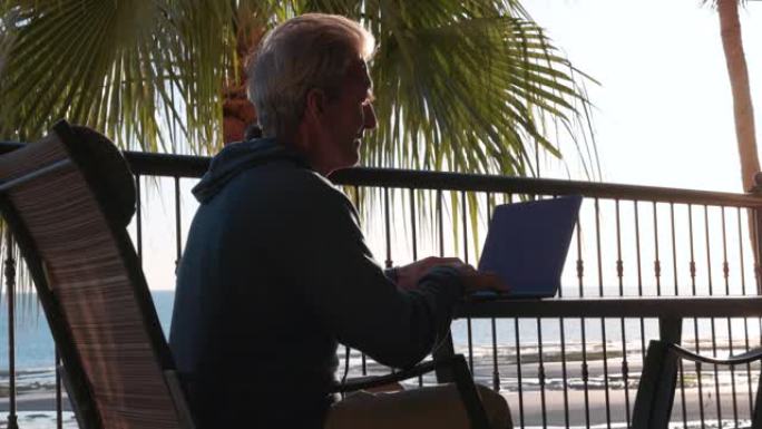 男子在热带露台上使用笔记本电脑
