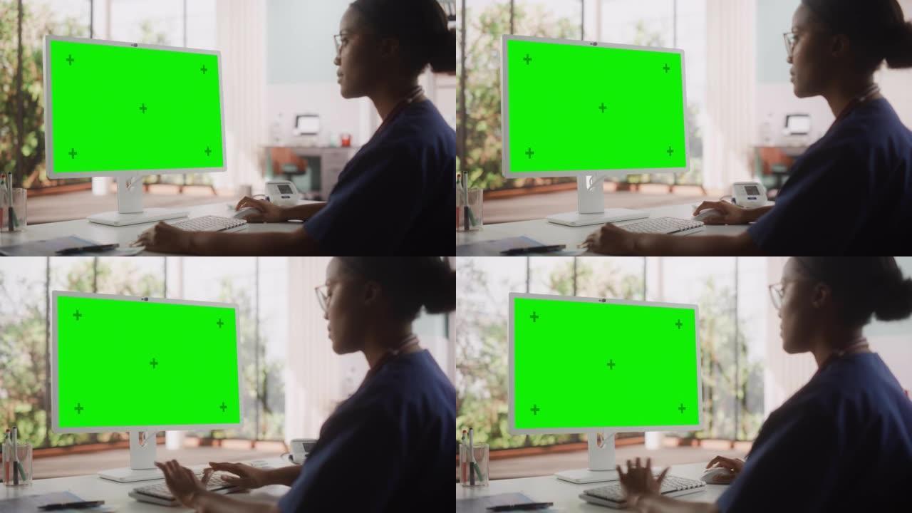非洲保健护士使用带有绿屏色度键显示的台式计算机进行日常医院操作。美丽的年轻诊所专业人员使用PC进行在