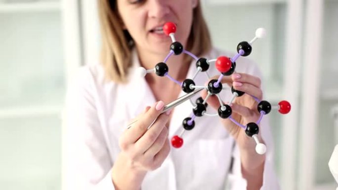 女科学家展示手中的分子结构模型并与学生交流