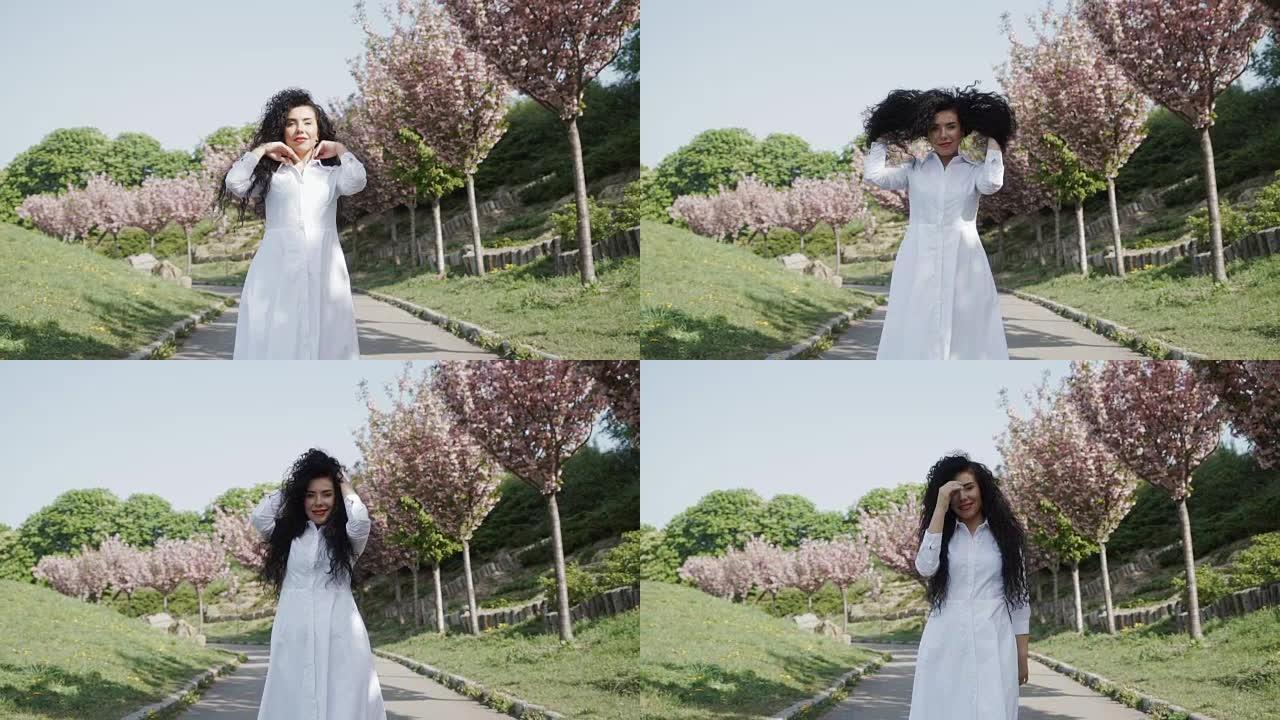 美丽的黑发女人走在公园的樱花巷