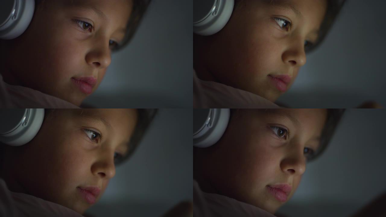 微距特写镜头，一个可爱的小女孩在睡觉前使用耳机和数字平板电脑玩游戏。女孩子晚上专注于屏幕，看视频，玩