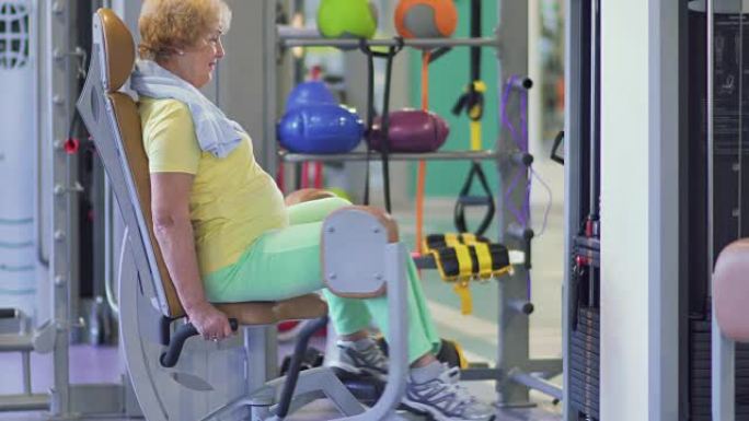 可爱的奶奶在健身房用训练设备训练她的腿