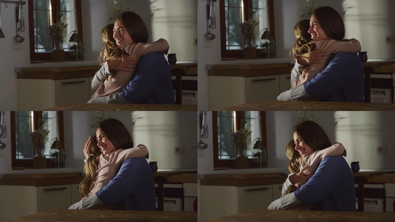 母亲和女儿在家里的厨房里拥抱的真实镜头。一个女人和她的小女孩之间表达母爱的情感时刻。他们互相拥抱