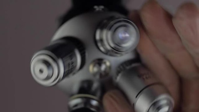 一只手旋转一块显微镜镜头，其中一个明亮地发光